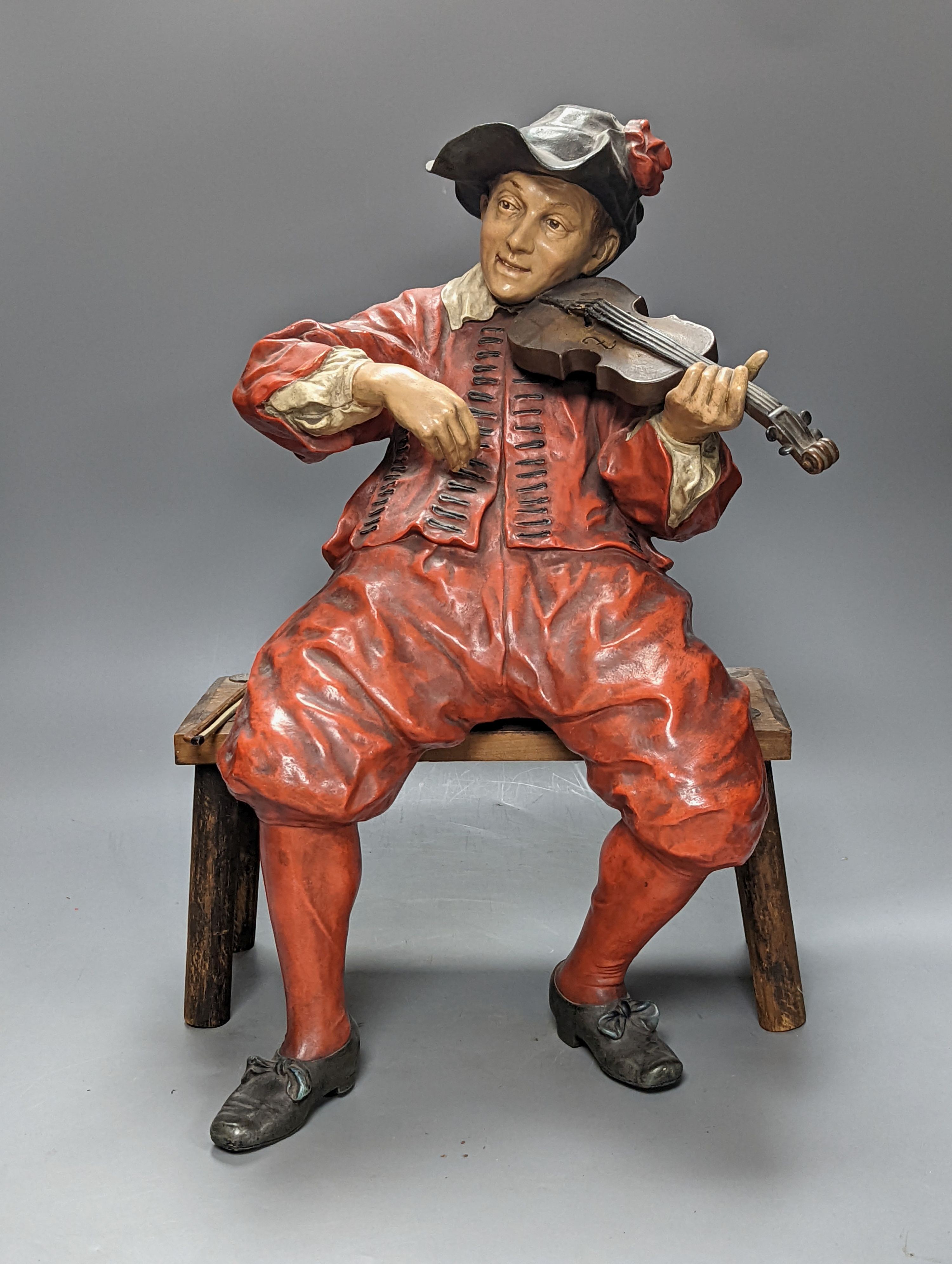 A pair of late 19th/early 20th century Austrian cold painted terracotta figures of musicians in 17th century dress, seated on wood stools 46cm